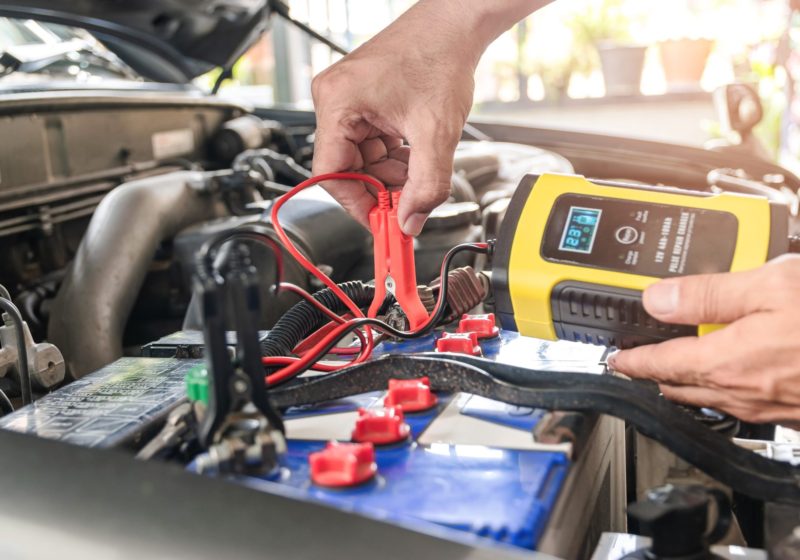 Accu The car mechanic is using a voltage measuring instrument and charging the battery, the car's battery power.